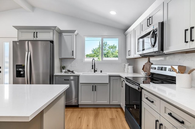 kitchen with sink, backsplash, lofted ceiling with beams, gray cabinetry, and appliances with stainless steel finishes