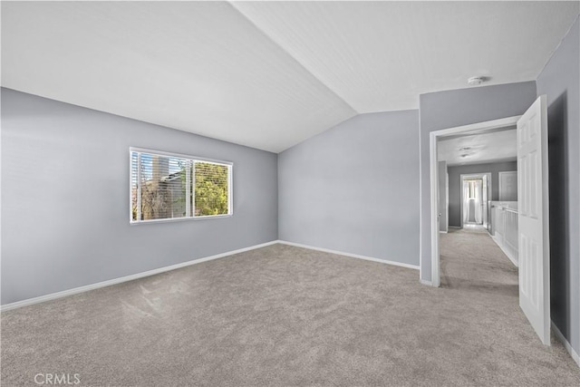 unfurnished room featuring lofted ceiling and light colored carpet