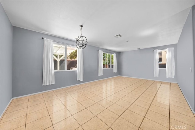 spare room with an inviting chandelier and light tile patterned flooring