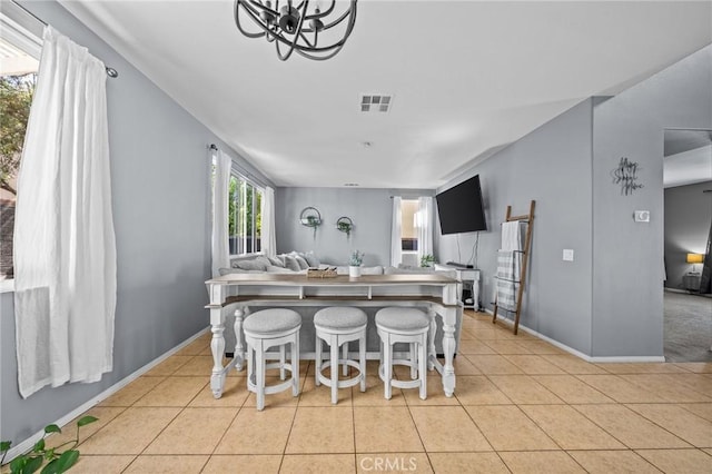 kitchen featuring a kitchen bar, an inviting chandelier, and light tile patterned floors