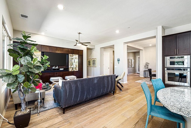 living room with ceiling fan and light hardwood / wood-style flooring