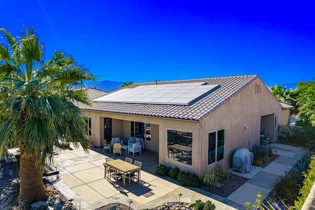 rear view of house featuring an outdoor hangout area, a patio area, cooling unit, and solar panels