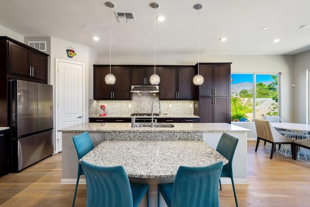 kitchen featuring decorative light fixtures, stainless steel fridge, and sink