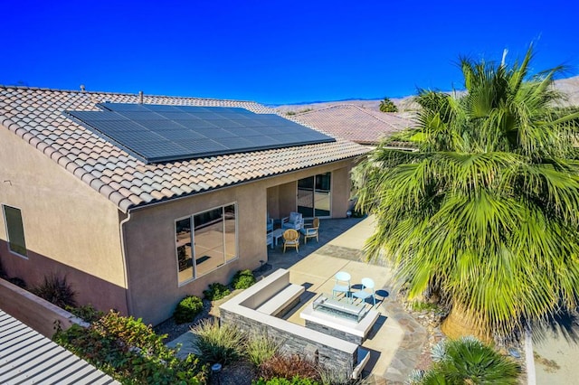 back of house with solar panels and a patio