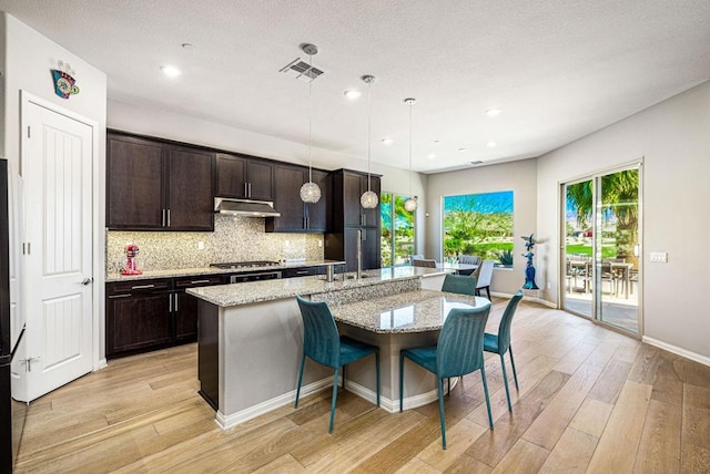 kitchen featuring a breakfast bar, pendant lighting, sink, and an island with sink