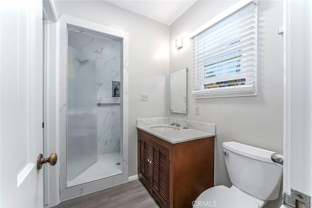 bathroom featuring vanity, hardwood / wood-style floors, toilet, and tiled shower