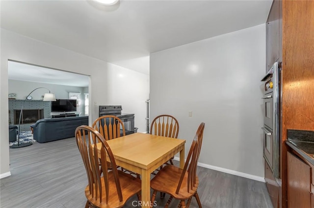 dining area with dark wood-type flooring and a brick fireplace