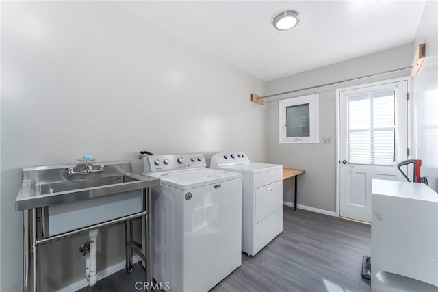 clothes washing area with washing machine and clothes dryer, sink, and hardwood / wood-style floors