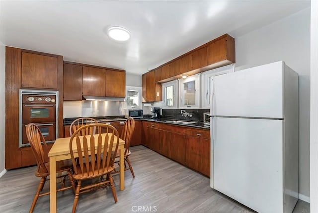 kitchen featuring sink, double wall oven, light hardwood / wood-style floors, and white refrigerator