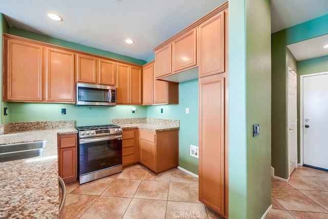 kitchen featuring light stone counters, stainless steel appliances, light tile patterned flooring, and sink