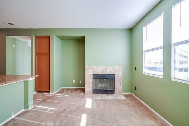 unfurnished living room featuring a tile fireplace and light carpet