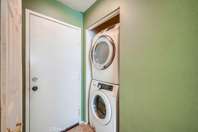 laundry room with stacked washer and dryer and light tile patterned floors