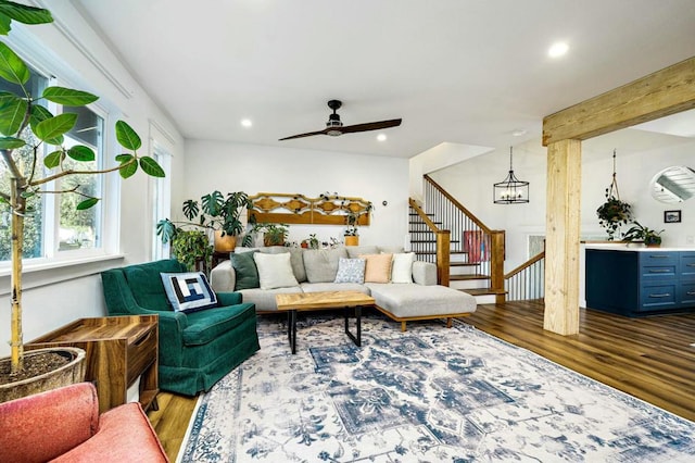 living room featuring ceiling fan with notable chandelier, dark hardwood / wood-style flooring, and beam ceiling