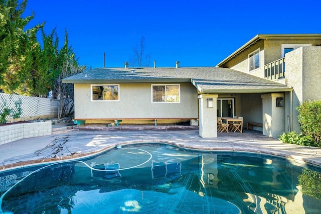 rear view of property with a fenced in pool and a patio