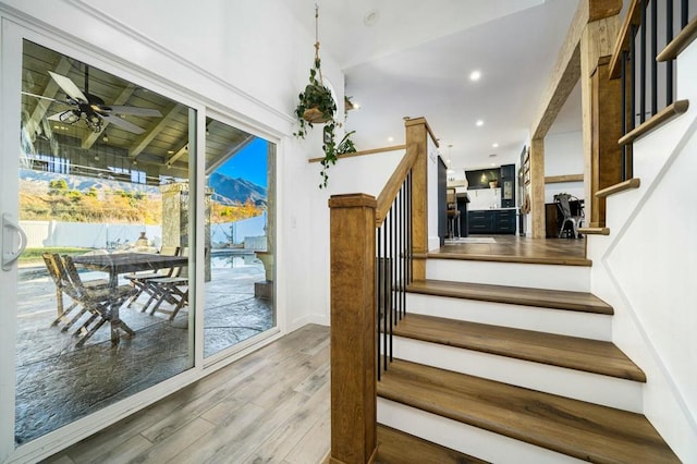 stairway with a wealth of natural light, ceiling fan, and wood-type flooring