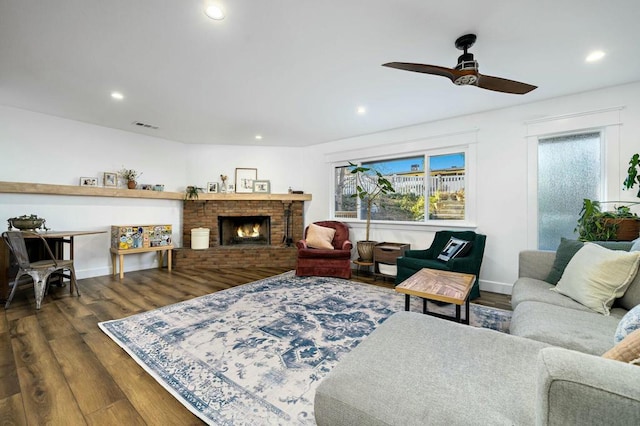 living room featuring dark hardwood / wood-style flooring, a fireplace, and ceiling fan