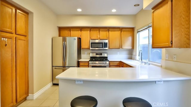 kitchen featuring kitchen peninsula, sink, a kitchen breakfast bar, stainless steel appliances, and light tile patterned floors