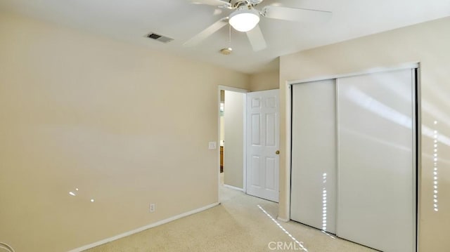 unfurnished bedroom featuring ceiling fan, a closet, and light carpet