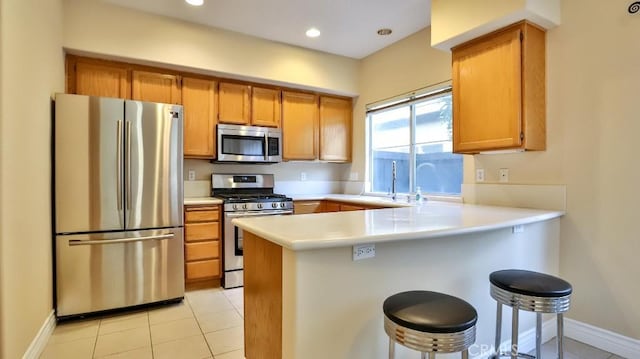 kitchen featuring a kitchen breakfast bar, stainless steel appliances, light tile patterned flooring, and kitchen peninsula