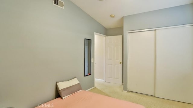 unfurnished bedroom with light carpet, a closet, and vaulted ceiling