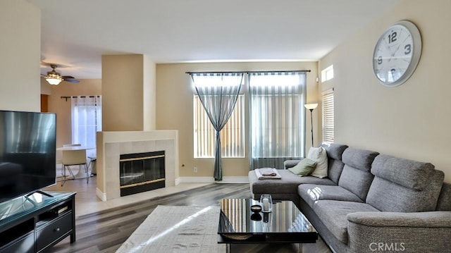 living room featuring ceiling fan, dark hardwood / wood-style flooring, and a tiled fireplace