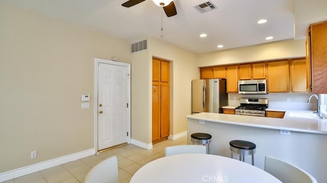 kitchen with kitchen peninsula, ceiling fan, appliances with stainless steel finishes, light tile patterned flooring, and sink