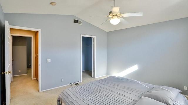 bedroom featuring light carpet, ceiling fan, a closet, lofted ceiling, and a walk in closet