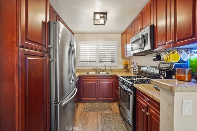 kitchen featuring dark wood-type flooring, a sink, light stone counters, stainless steel appliances, and dark brown cabinets