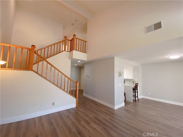 1911 E Calico Dr, West Covina, CA 91791 - unfurnished living room featuring wood finished floors, baseboards, stairway, and a towering ceiling
