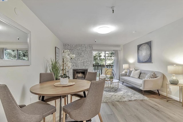 dining area featuring a stone fireplace and light wood-type flooring