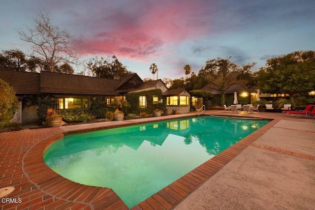 pool at dusk featuring a patio