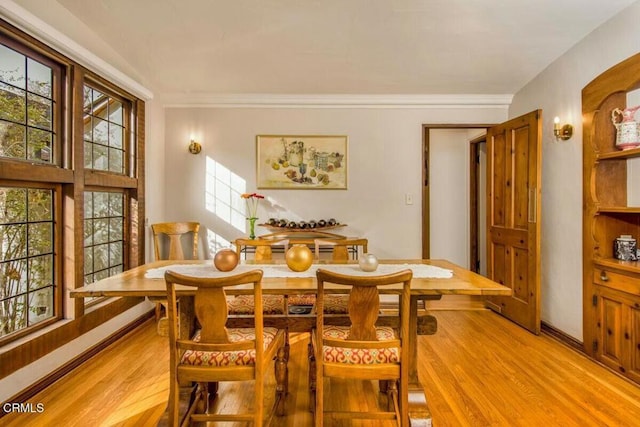 dining room with a wealth of natural light, crown molding, and light hardwood / wood-style flooring