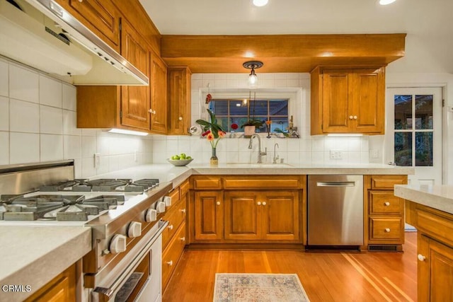 kitchen featuring pendant lighting, stainless steel appliances, light hardwood / wood-style floors, backsplash, and sink