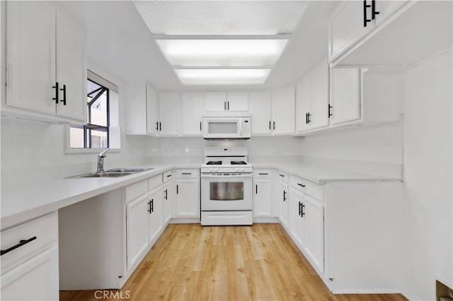 kitchen with white appliances, light wood-type flooring, decorative backsplash, white cabinets, and sink