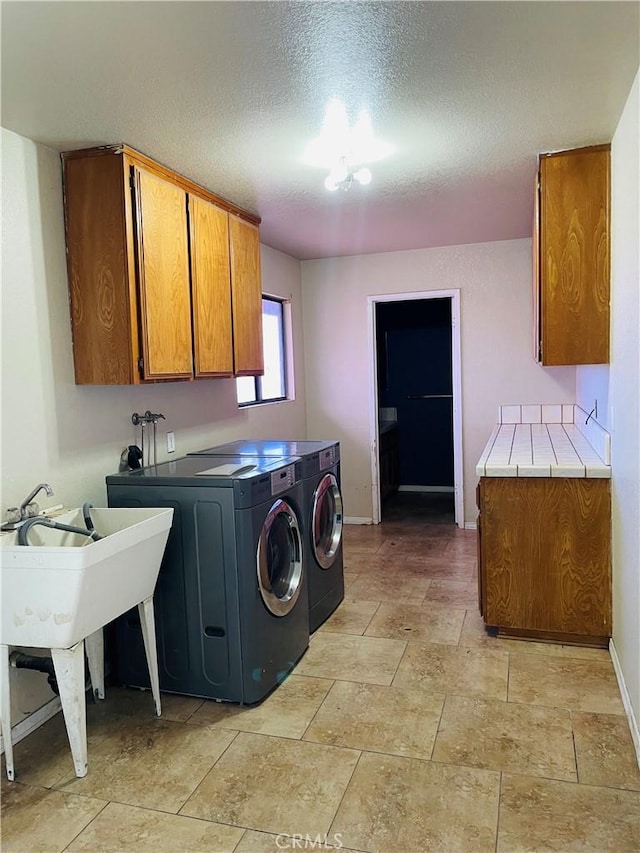 clothes washing area with independent washer and dryer, cabinets, and a textured ceiling