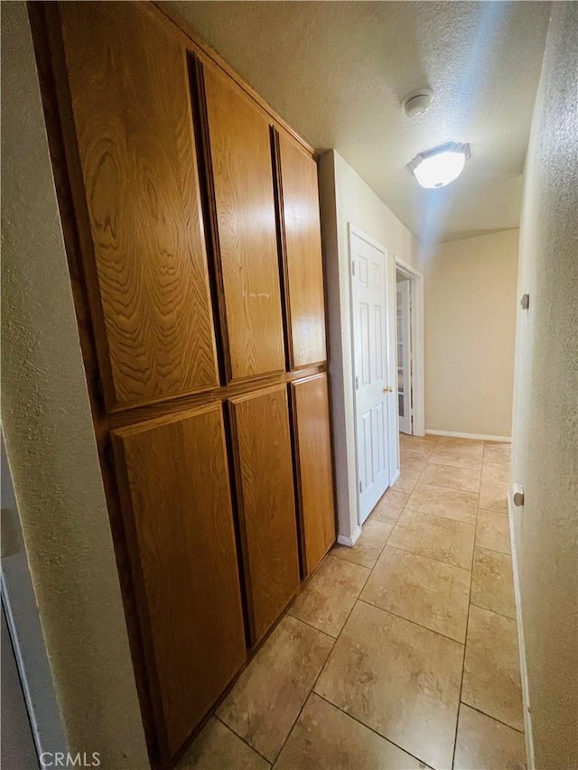 hall with light tile patterned flooring and a textured ceiling