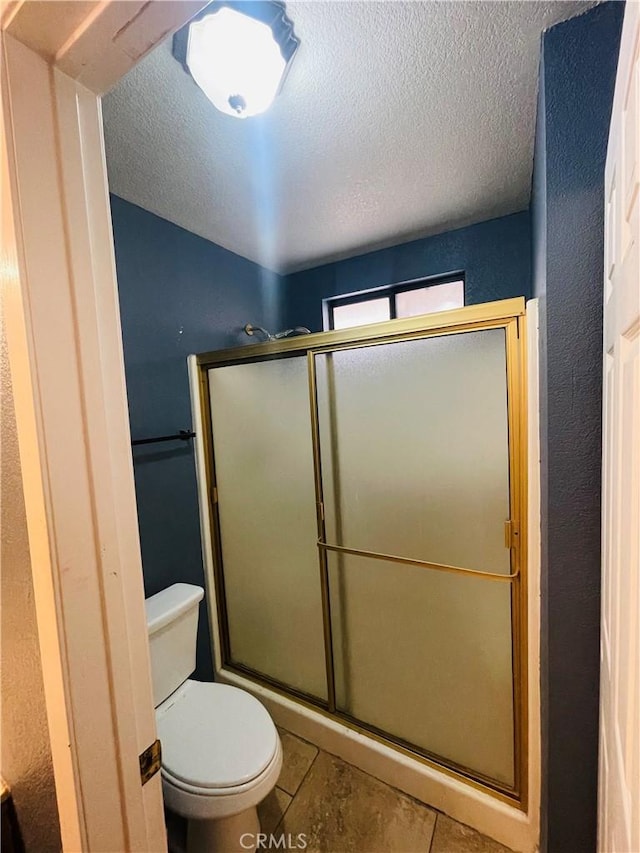 bathroom with a textured ceiling, a shower with shower door, tile patterned floors, and toilet