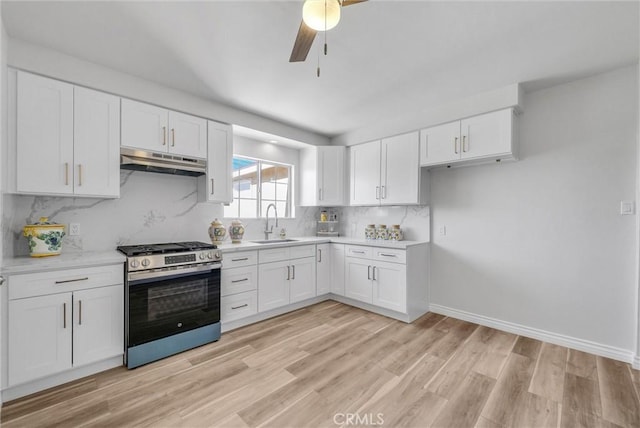 kitchen featuring white cabinets, backsplash, gas range, and sink