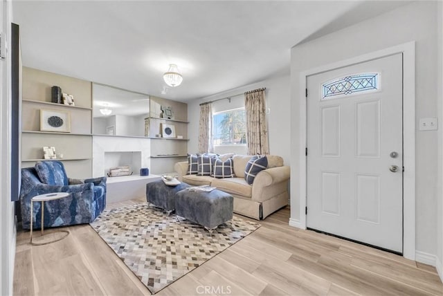 living room with built in shelves and light hardwood / wood-style floors