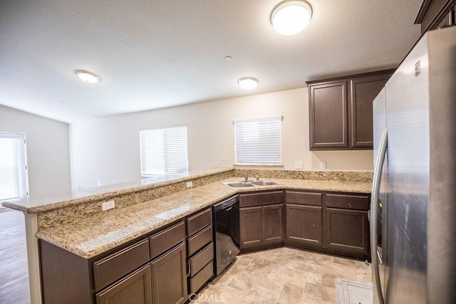 kitchen with kitchen peninsula, sink, stainless steel refrigerator, black dishwasher, and light stone countertops