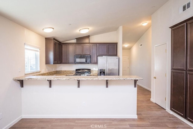 kitchen with kitchen peninsula, a breakfast bar, stainless steel refrigerator with ice dispenser, and dark brown cabinetry