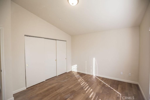 unfurnished bedroom featuring hardwood / wood-style floors, a closet, and lofted ceiling