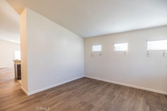 spare room featuring vaulted ceiling and dark wood-type flooring