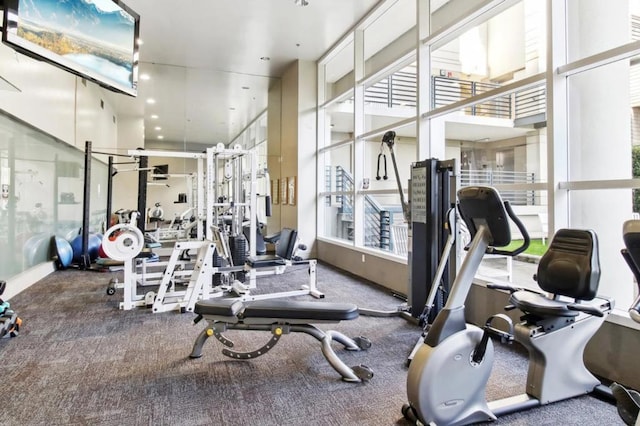 gym featuring a towering ceiling and carpet flooring