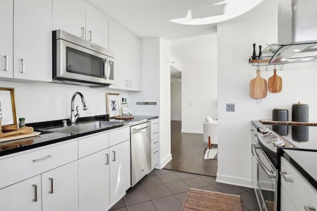 kitchen with white cabinetry, island range hood, stainless steel appliances, dark tile patterned flooring, and sink