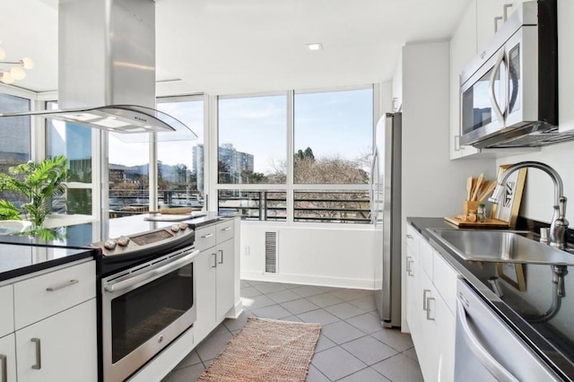 kitchen featuring white cabinets, island exhaust hood, stainless steel appliances, sink, and light tile patterned floors