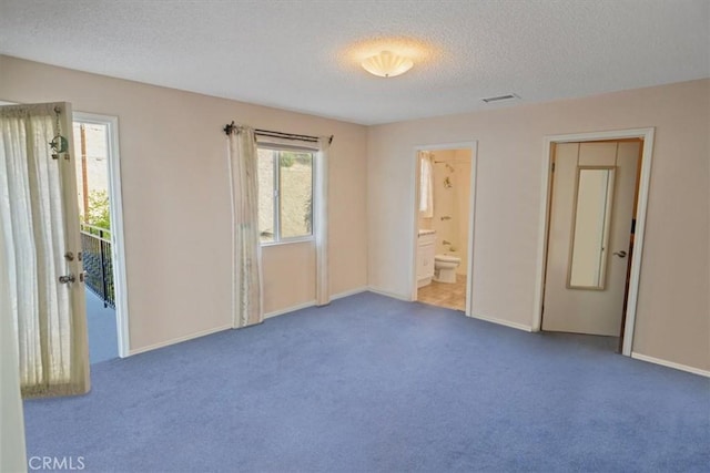 unfurnished bedroom with ensuite bathroom, carpet floors, and a textured ceiling