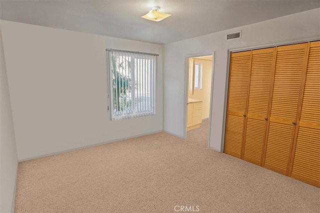 unfurnished bedroom with light colored carpet and a closet