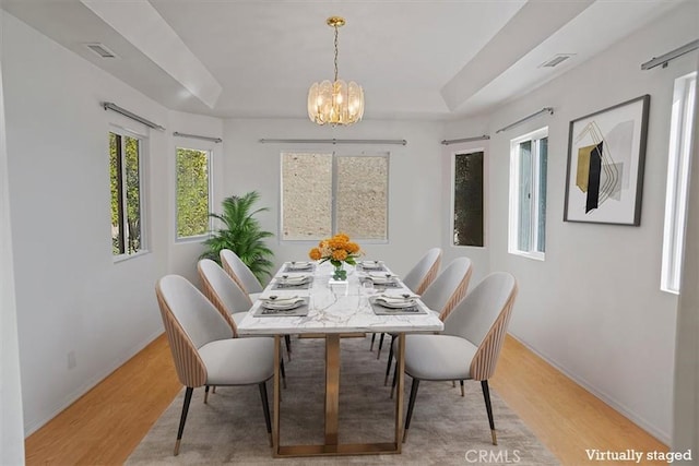 dining room featuring light hardwood / wood-style flooring, a raised ceiling, and a chandelier