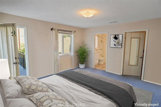 carpeted bedroom with ensuite bathroom and a textured ceiling